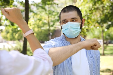 Photo of Man and woman bumping elbows to say hello outdoors. Keeping social distance during coronavirus pandemic