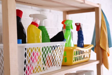 Many different detergents on wooden shelf near white brick wall