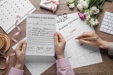 Women filling Wedding Checklists at wooden table, top view