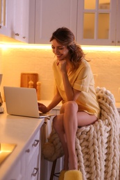 Beautiful young woman with laptop in kitchen. Weekend morning