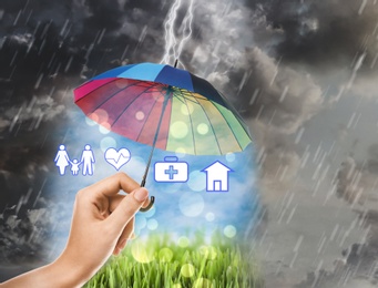 Insurance agent protecting illustrations with rainbow umbrella from storm, closeup