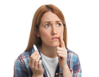 Upset woman with herpes applying cream on lips against white background