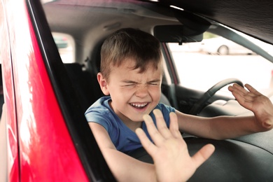 Photo of Crying little boy closed inside car. Child in danger
