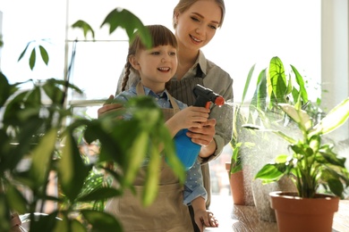 Mother and daughter taking care of home plants indoors