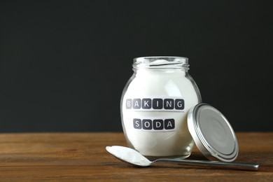 Jar and spoon with baking soda on wooden table. Space for text