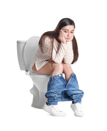 Upset woman sitting on toilet bowl, white background