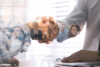 Double exposure of team workers and business partners shaking hands in office, closeup 