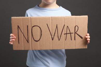 Boy holding poster No War against background, closeup
