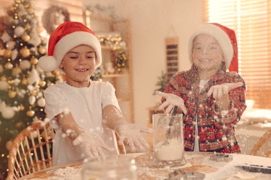 Cute little children having fun while making delicious Christmas cookies at home