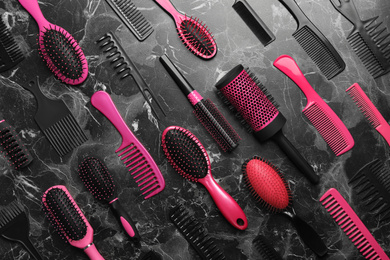 Flat lay composition with hair brushes and combs on black marble background