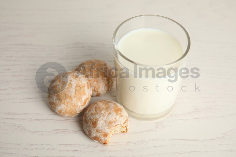 Photo of Tasty homemade gingerbread cookies and glass of milk on white wooden table