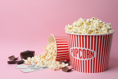 Popcorn, tickets and film footage on pink background. Cinema snack
