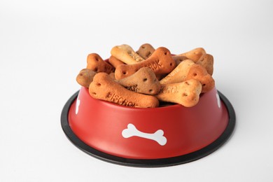 Photo of Bone shaped dog cookies in feeding bowl on white background