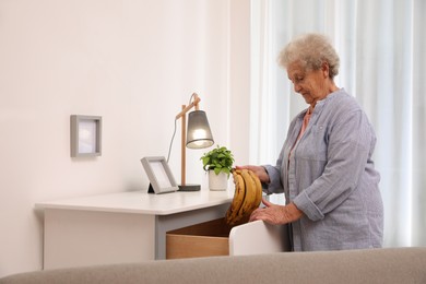 Senior woman finding bananas in chest of drawers at home. Age-related memory impairment