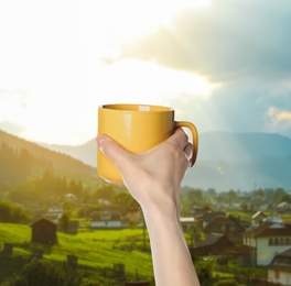 Closeness to nature. Woman holding cup in mountain village, closeup