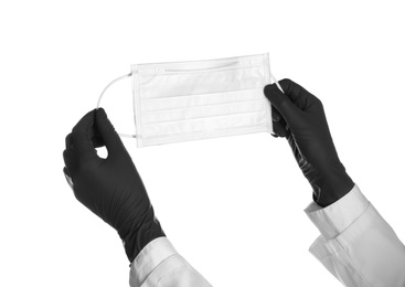 Doctor in sterile gloves holding medical face mask on white background