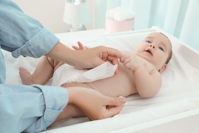 Photo of Mother changing baby's diaper at home, focus on hands