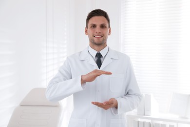 Happy male dentist holding something in clinic