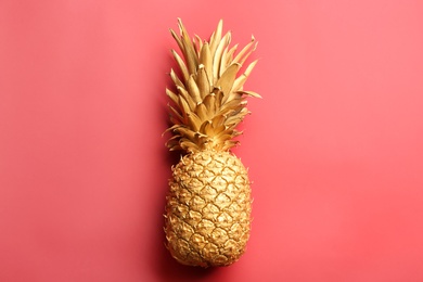 Photo of Painted golden pineapple on red background, top view. Creative concept