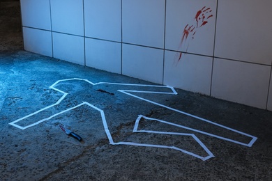 Crime scene with chalk outline, knife and blood marks on floor. Detective investigation