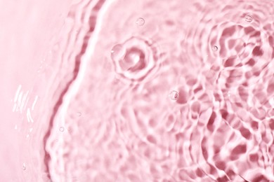 Closeup view of water with rippled surface on pink background