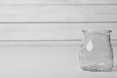 Empty glass jar on white table, space for text