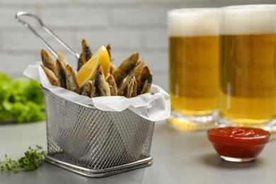 Photo of Delicious fried anchovies, sauce and glasses with beer on table. Space for text