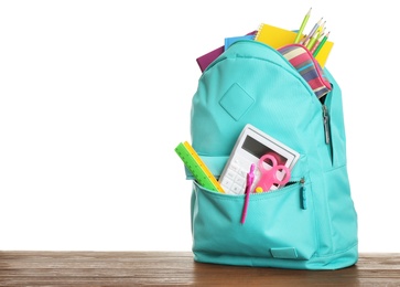 Stylish backpack with different school stationary on wooden table against white background