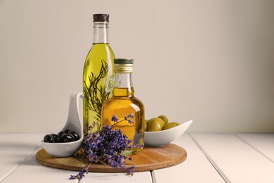 Different cooking oils and ingredients on white wooden table against light background