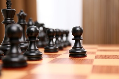 Pawn piece leading others on chessboard indoors