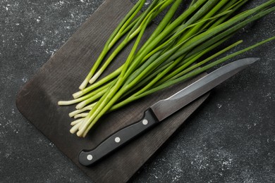 Fresh green onion and knife on black table, top view