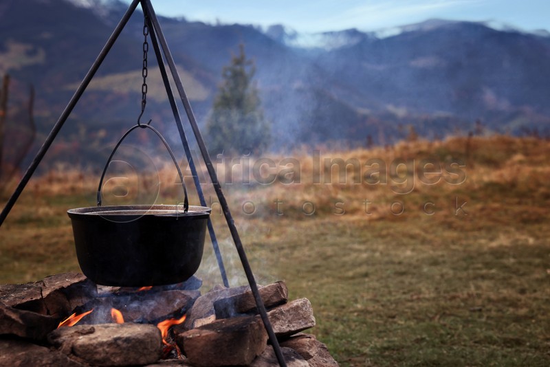 Cooking food on campfire in mountains on autumn day. Camping season