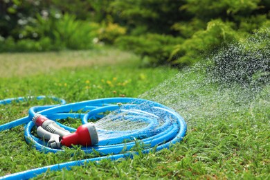 Water spraying from hose on green grass outdoors