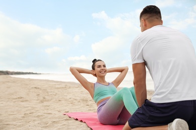 Couple doing exercise together on beach, space for text. Body training