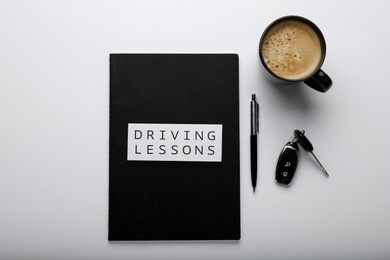 Composition with workbook for driving lessons on white background, top view. Passing license exam