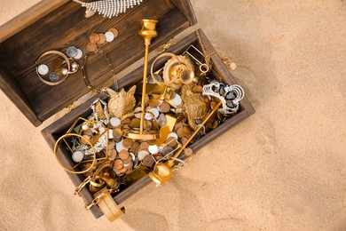 Open wooden treasure chest on sand, above view. Space for text