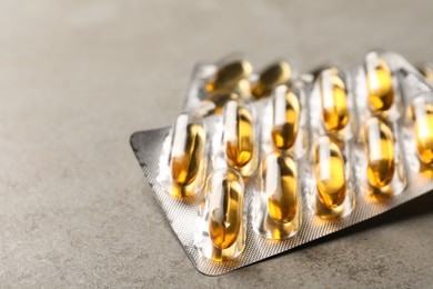 Photo of Dietary supplement capsules in blister packs on grey table, closeup. Space for text