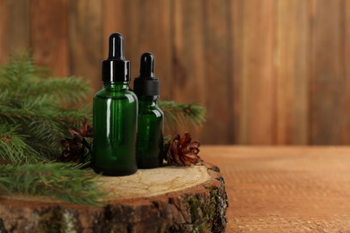 Pine essential oil, cones and branches on wooden table. Space for text
