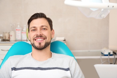 Happy man having dentist's appointment in modern clinic. Space for text
