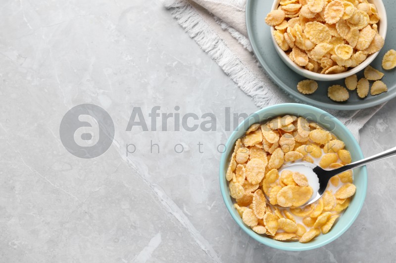 Tasty cornflakes with milk served on light grey table, flat lay. Space for text