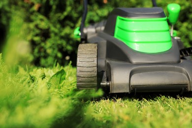Photo of Cutting green grass with lawn mower in garden, closeup