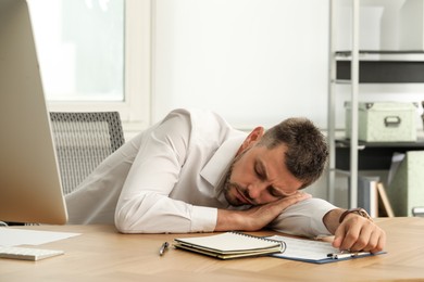 Photo of Tired man sleeping at workplace in office