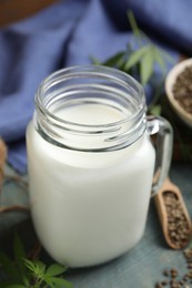 Mason jar of fresh hemp milk on light blue wooden table