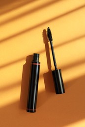 Mascara for eyelashes on orange background, flat lay. Makeup product