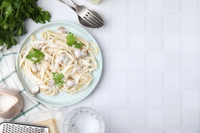 Photo of Delicious pasta with mushrooms served on white tiled table, flat lay. Space for text