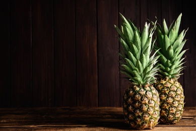 Photo of Fresh ripe juicy pineapples on wooden table. Space for text