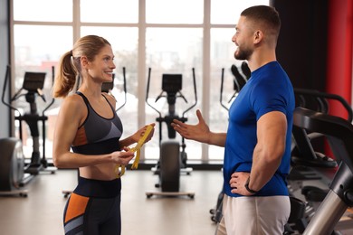 Photo of Trainer having discussion with woman in gym