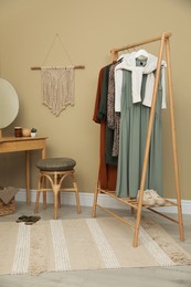 Modern dressing room interior with clothing rack, wooden table and mirror