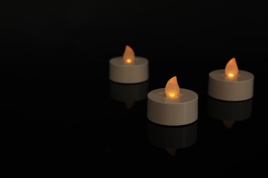 Glowing decorative LED candles on black background. Space for text