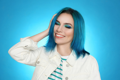 Photo of Young woman with bright dyed hair on light blue background